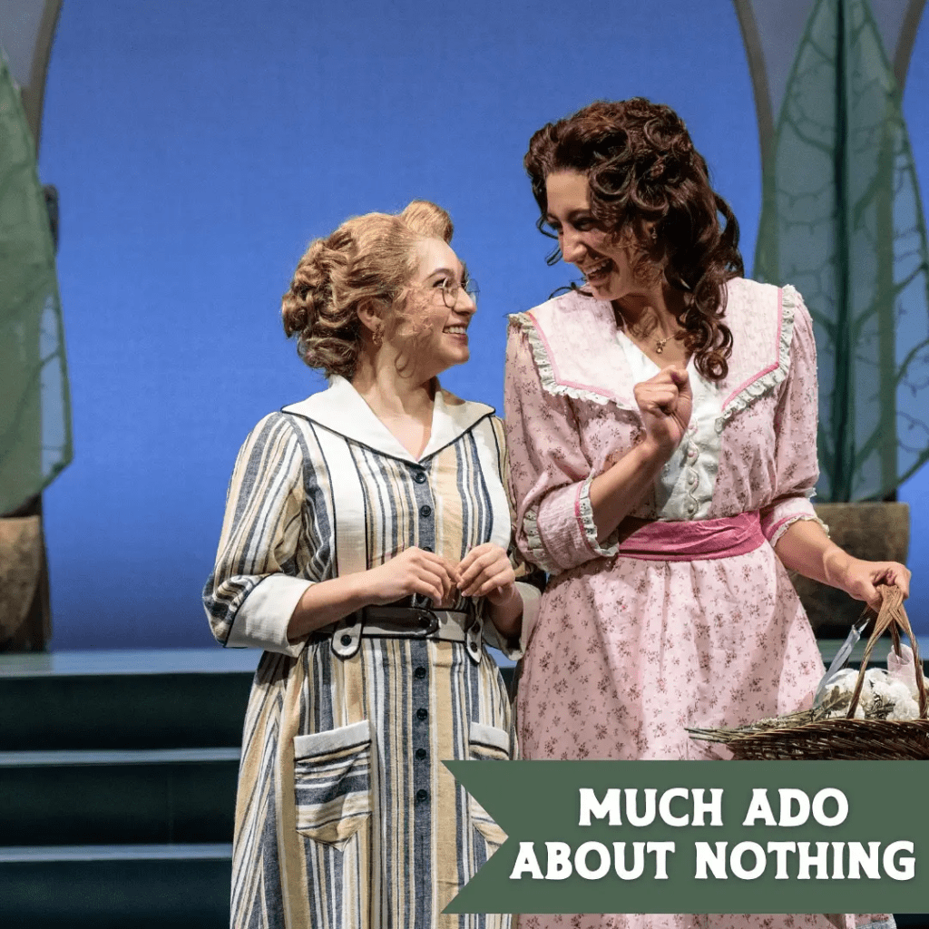 Two actresses smiling and engaging in a friendly conversation on stage during a scene from 'Much Ado About Nothing', with a whimsical set design in the background.