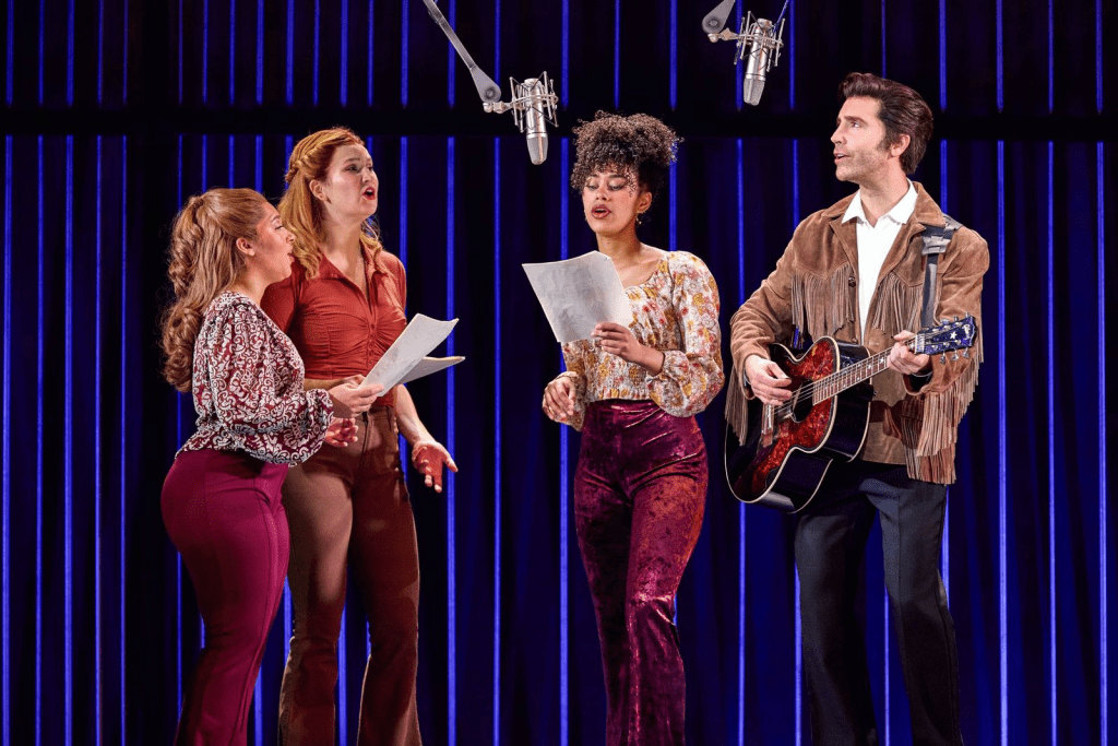 Review: "A Beautiful Noise" Brings Neil Diamond's Music to Life at Salt Lake City’s Eccles Theater 4 Four singers performing on stage with microphones while holding sheets of music. The scene is vibrant, with colorful outfits and a dramatic backdrop.