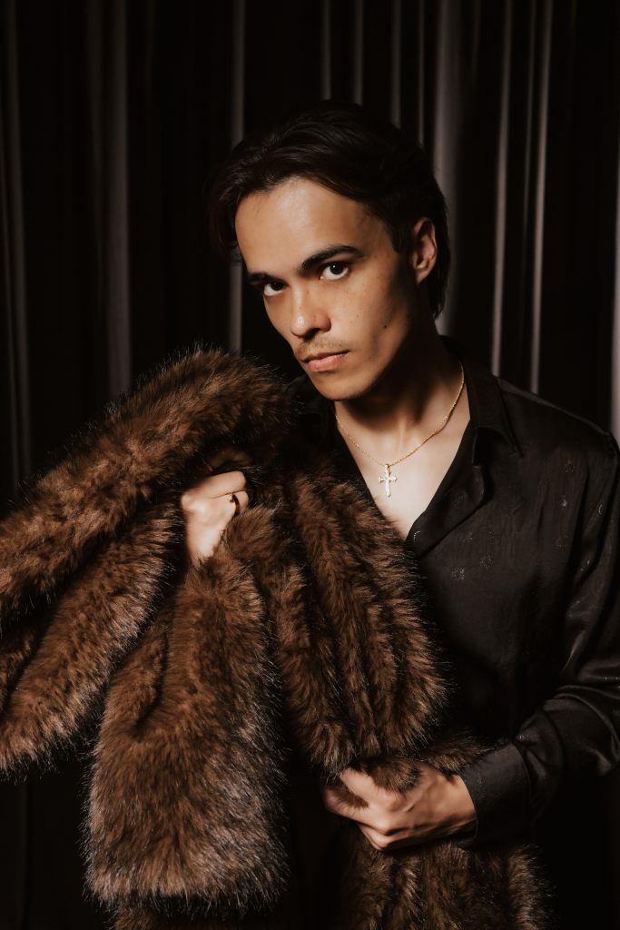 Promotional photo for Venus in Fur: a man in a black shirt holds a fur coat over his shoulder.